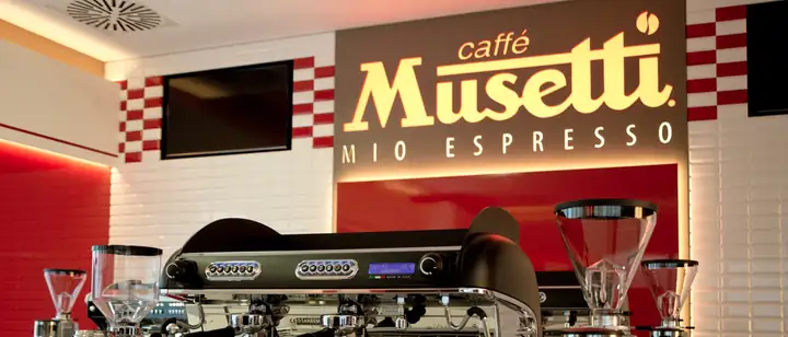 Професионален апарат за еспресо и мелници пред логото Musetti